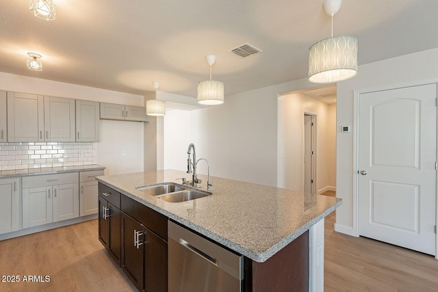 kitchen with a sink, visible vents, light wood-type flooring, and stainless steel dishwasher