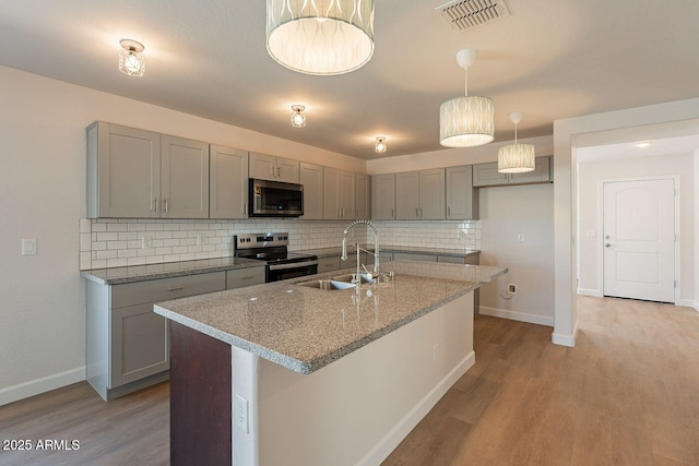 kitchen with visible vents, gray cabinetry, light wood-style flooring, stainless steel appliances, and a sink