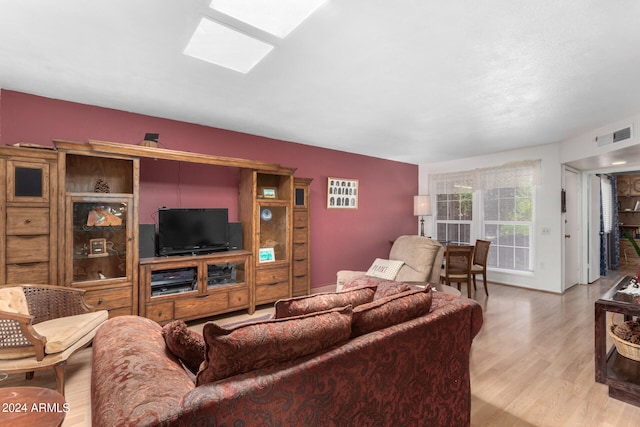 living room with light hardwood / wood-style flooring and a skylight