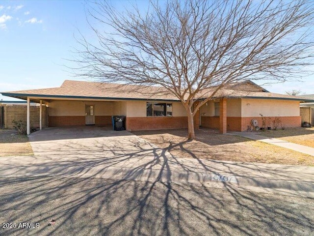 single story home with a carport, stucco siding, concrete driveway, and brick siding