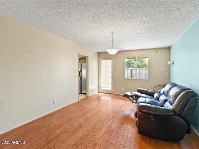 living area featuring a textured ceiling, hardwood / wood-style floors, and baseboards