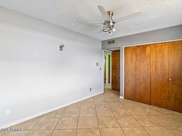 unfurnished bedroom featuring light tile patterned floors, a closet, visible vents, a textured ceiling, and baseboards