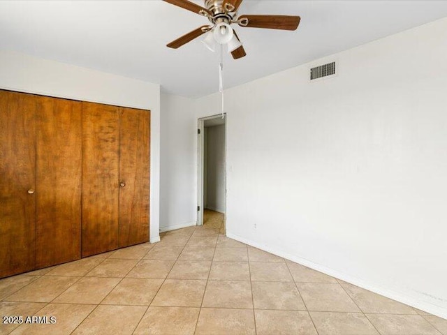 unfurnished bedroom with light tile patterned floors, baseboards, visible vents, ceiling fan, and a closet