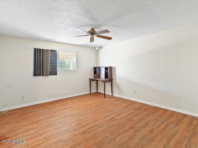 unfurnished room with a textured ceiling, light wood-type flooring, a ceiling fan, and baseboards