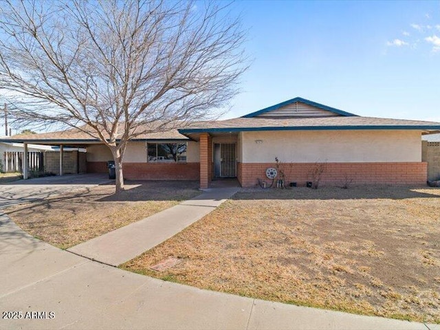 ranch-style house featuring a front lawn, an attached carport, and brick siding