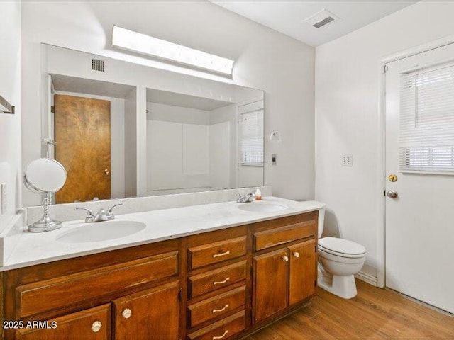 full bath featuring toilet, visible vents, a sink, and wood finished floors