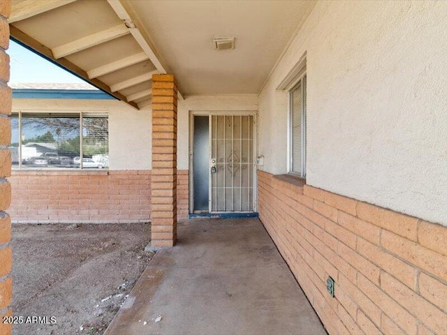 view of exterior entry with stucco siding and brick siding