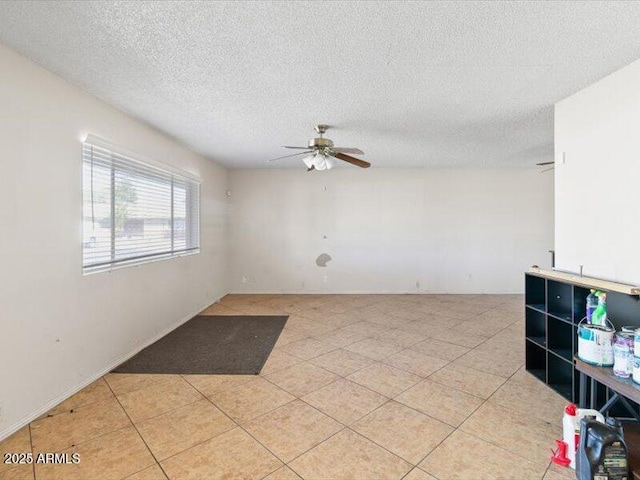 spare room featuring a ceiling fan, a textured ceiling, and light tile patterned floors