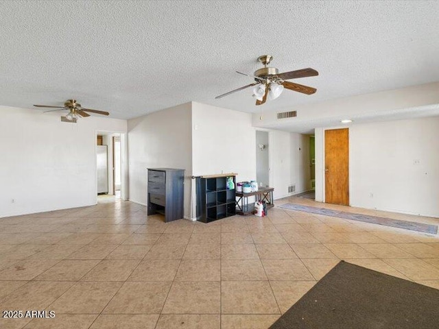 unfurnished living room with ceiling fan, a textured ceiling, light tile patterned flooring, and visible vents