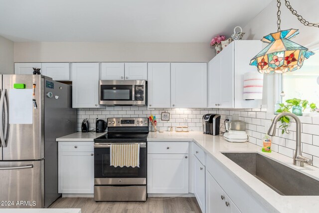 kitchen featuring sink, stainless steel appliances, white cabinets, and light hardwood / wood-style floors