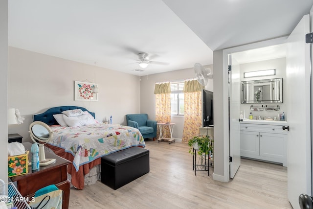 bedroom with light wood finished floors, ensuite bathroom, baseboards, and a sink