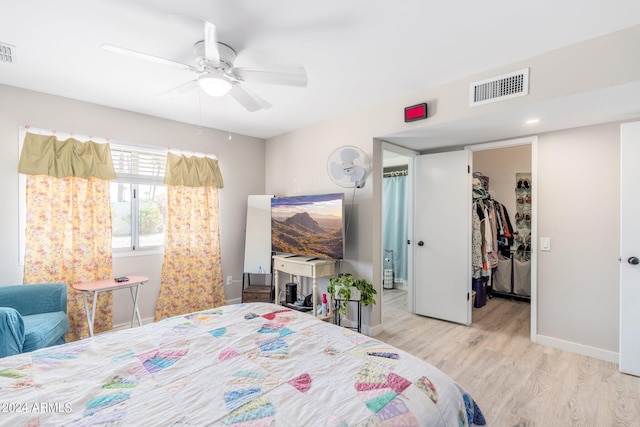 bedroom with light wood-type flooring, a spacious closet, ceiling fan, and a closet