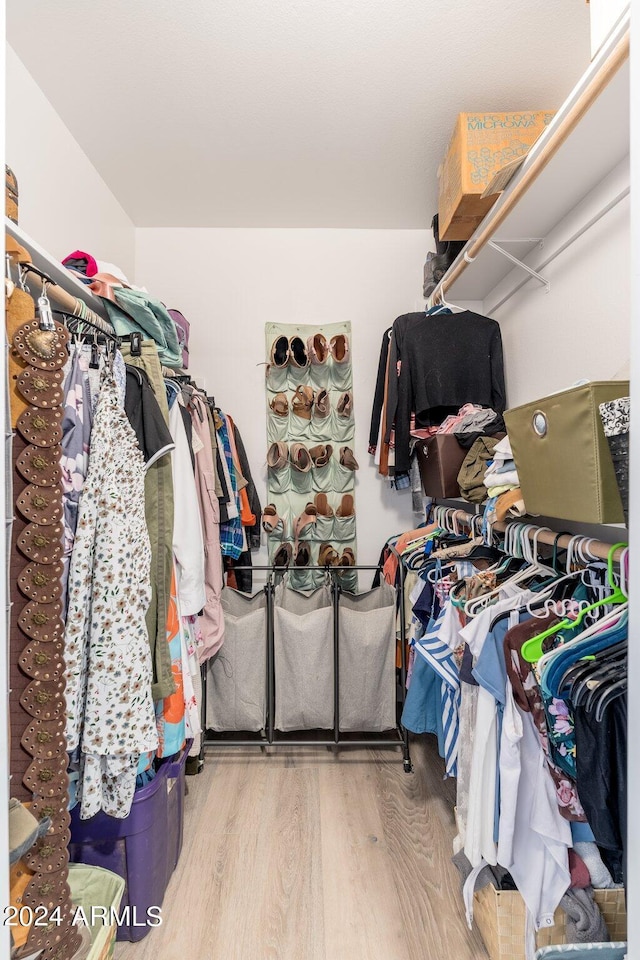 walk in closet with wood finished floors