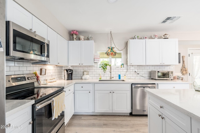 kitchen with visible vents, a toaster, a sink, stainless steel appliances, and white cabinets