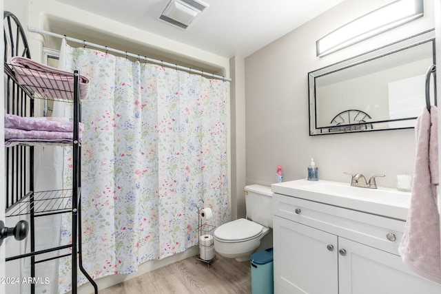 bathroom featuring vanity, toilet, hardwood / wood-style flooring, and curtained shower