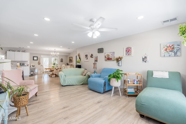 living room with ceiling fan with notable chandelier and light wood-type flooring