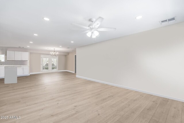 living room with ceiling fan with notable chandelier and light hardwood / wood-style floors