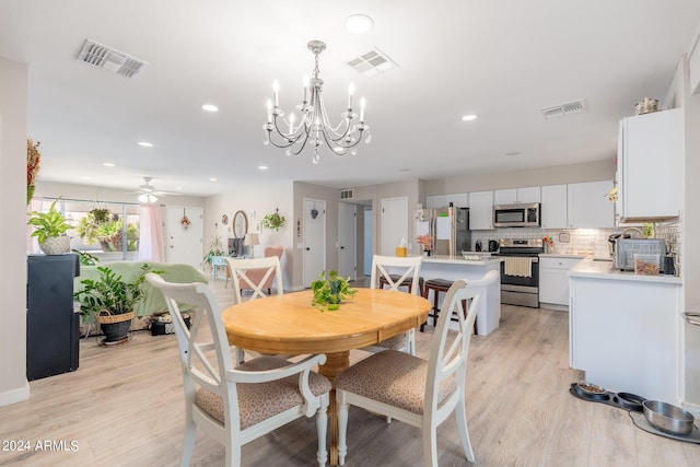 dining space with ceiling fan with notable chandelier and light hardwood / wood-style flooring