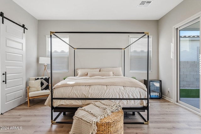 bedroom featuring a barn door, access to outside, and light hardwood / wood-style floors