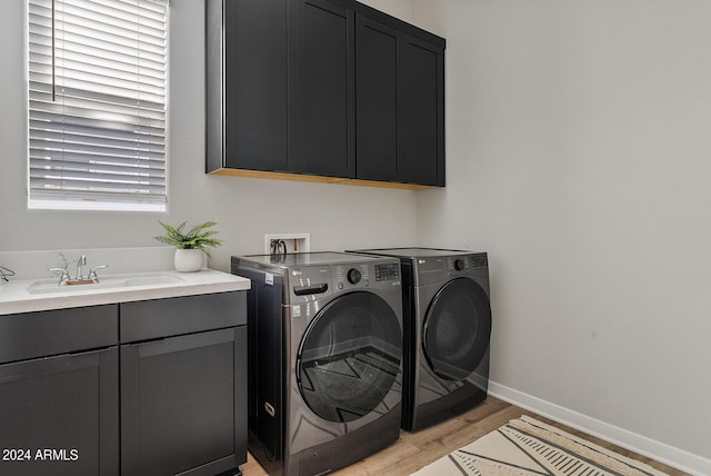 washroom featuring washer and dryer, sink, light hardwood / wood-style flooring, and cabinets