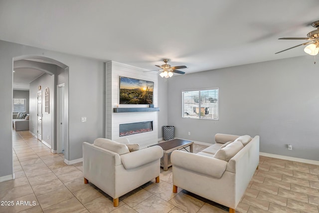 tiled living room with a large fireplace and ceiling fan