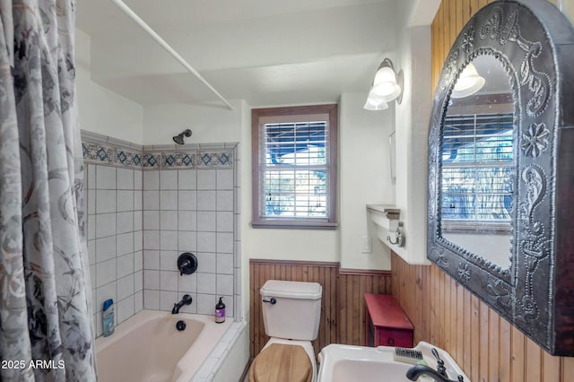 full bathroom with toilet, shower / bathtub combination with curtain, sink, and wood walls