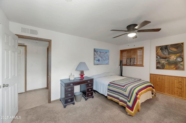 carpeted bedroom with ceiling fan and wood walls