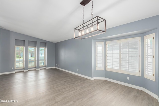 spare room featuring wood-type flooring and vaulted ceiling