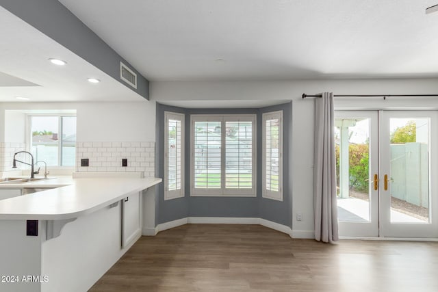 kitchen with french doors, sink, light wood-type flooring, tasteful backsplash, and kitchen peninsula