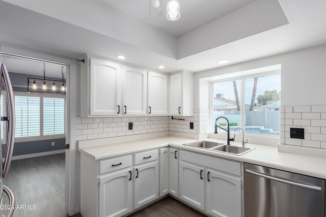 kitchen featuring white cabinets, dishwasher, decorative backsplash, and sink