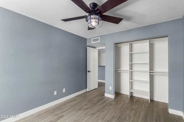 unfurnished bedroom with hardwood / wood-style floors, a closet, and ceiling fan