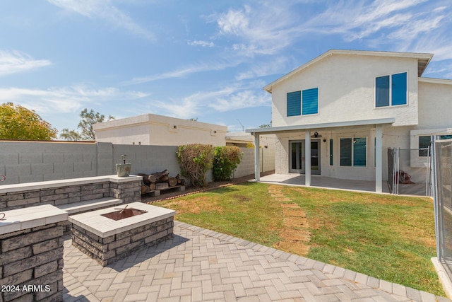 back of house with a lawn, ceiling fan, an outdoor fire pit, and a patio