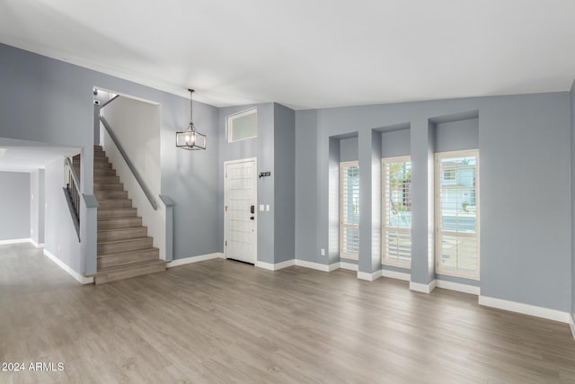 unfurnished living room featuring vaulted ceiling, hardwood / wood-style flooring, and an inviting chandelier