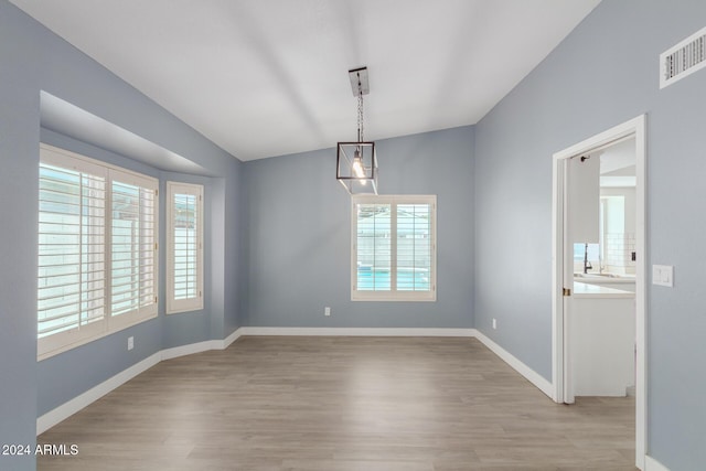 unfurnished dining area featuring lofted ceiling and light wood-type flooring