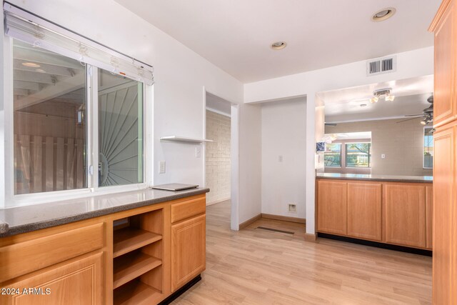 kitchen with stone counters, ceiling fan, and light wood-type flooring