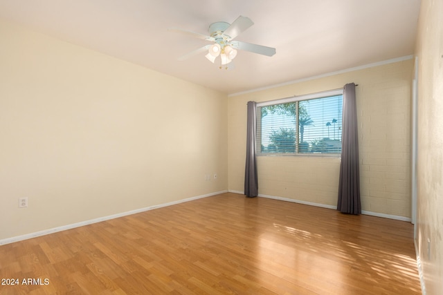 empty room featuring ceiling fan, wood-type flooring, and ornamental molding