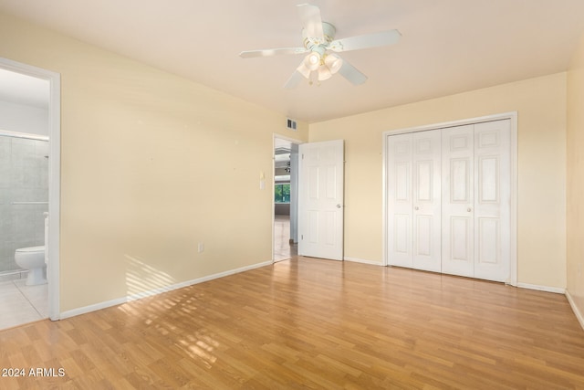 unfurnished bedroom with ensuite bathroom, a closet, ceiling fan, and light wood-type flooring