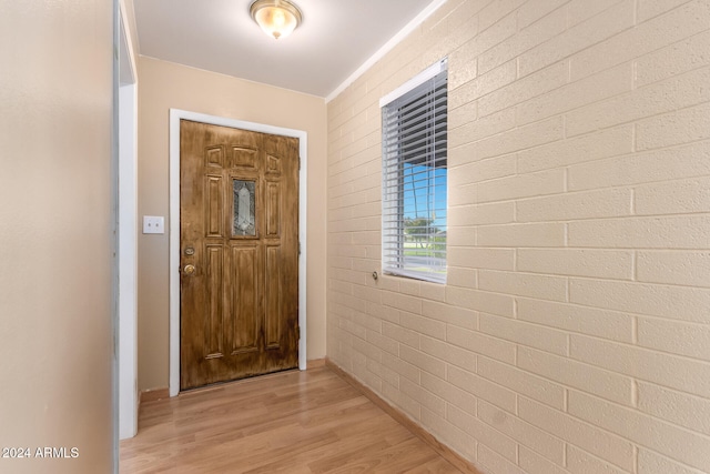 corridor with brick wall and light hardwood / wood-style flooring