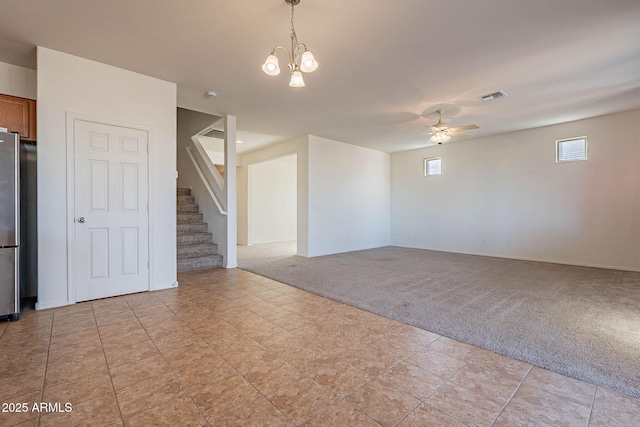 spare room featuring ceiling fan with notable chandelier and light carpet