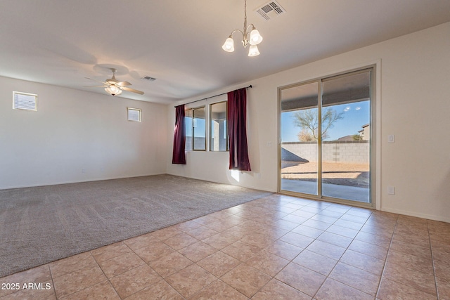 empty room featuring light tile patterned floors and ceiling fan with notable chandelier