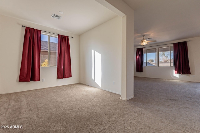 carpeted empty room featuring ceiling fan and plenty of natural light