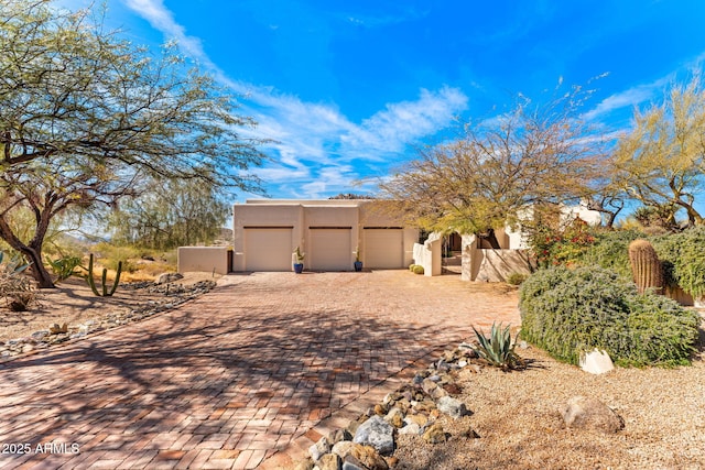 exterior space with decorative driveway, an attached garage, and stucco siding