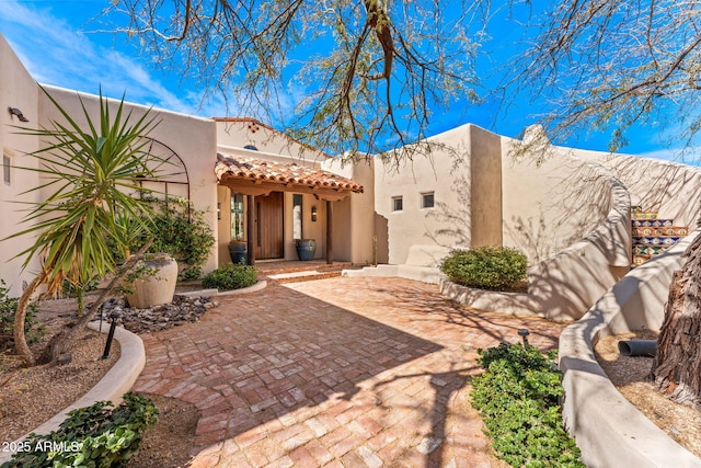 rear view of property featuring a tiled roof and stucco siding