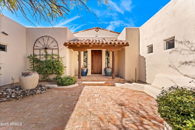 doorway to property featuring a tile roof and stucco siding