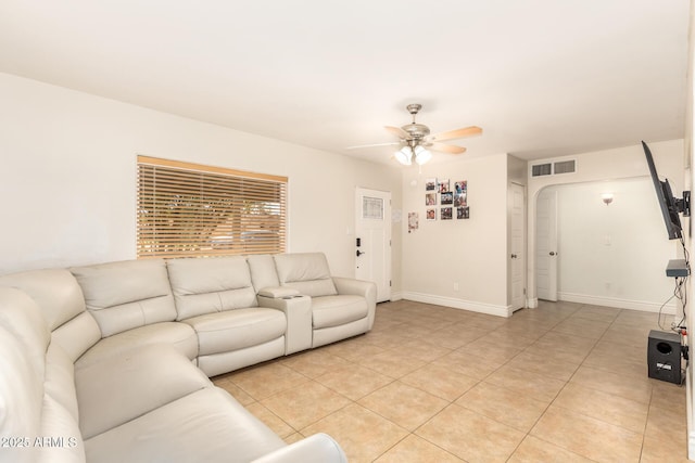 living area featuring light tile patterned floors, a ceiling fan, visible vents, baseboards, and arched walkways