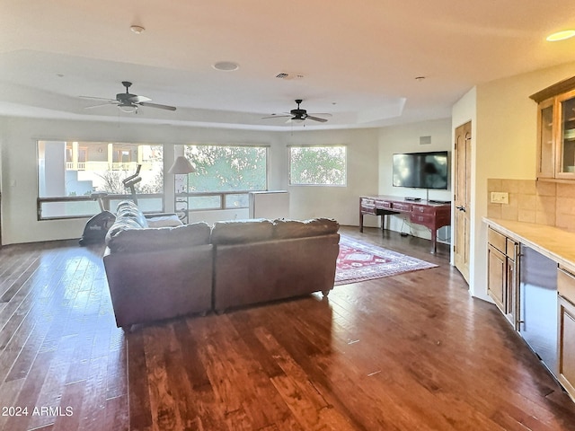 living room with ceiling fan, dark hardwood / wood-style floors, and a raised ceiling