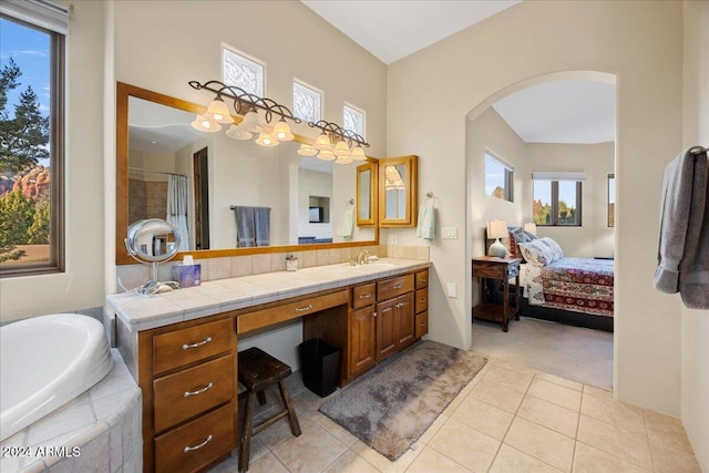 bathroom with vanity, tile patterned flooring, and a relaxing tiled tub