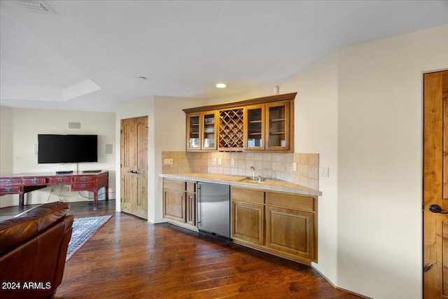 kitchen with tasteful backsplash, stainless steel refrigerator, sink, tile counters, and dark wood-type flooring