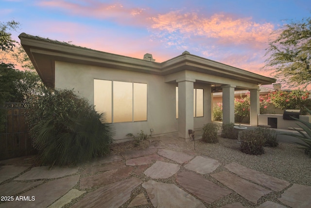 back house at dusk featuring a patio