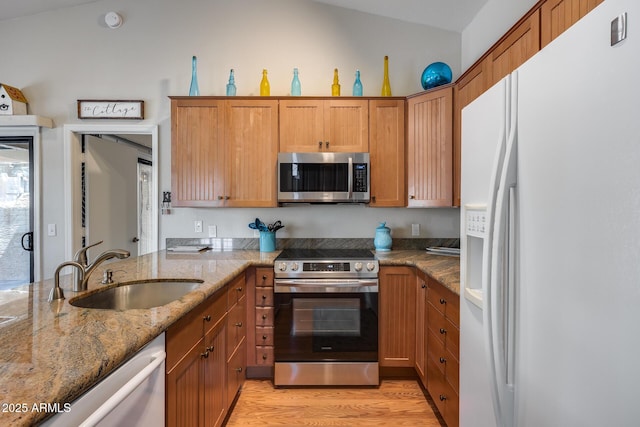 14300 W Bell Rd Unit 312, Surprise, AZ 85374 - kitchen featuring appliances with stainless steel finishes, a sink, light wood-style flooring, stone counters, and lofted ceiling